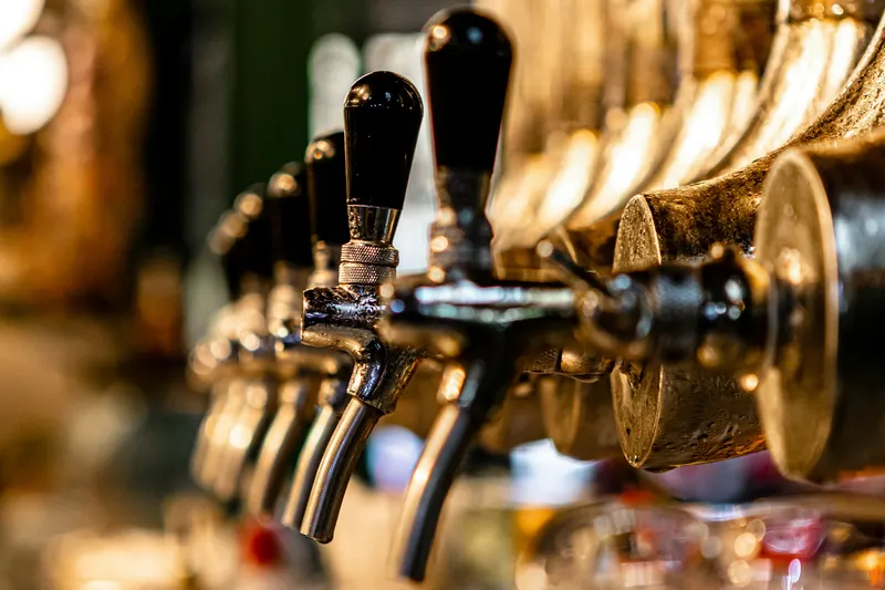 A row of brass beer taps behind a bar.
