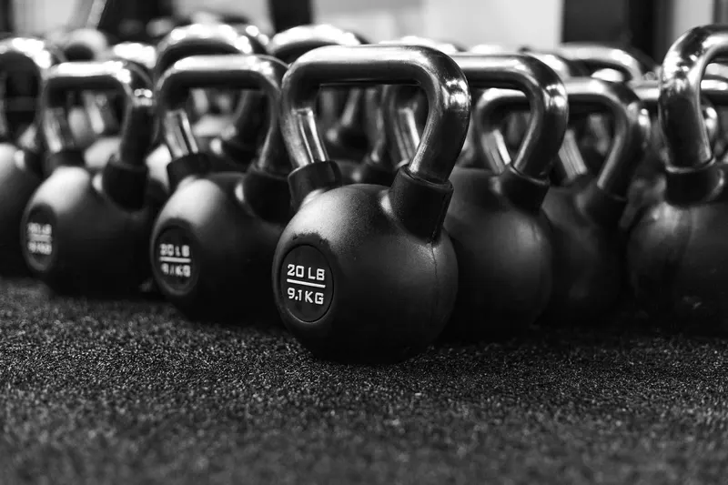 A row of black kettlebells on a gym floor.